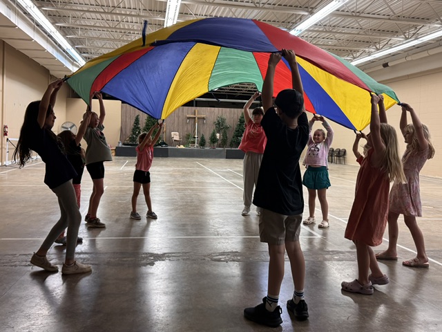 Kids playing beneath a raised parachute